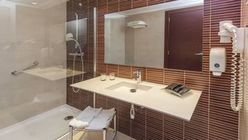 A modern bathroom with a glass-enclosed shower, a white sink with a mirror above it, and a towel rack.