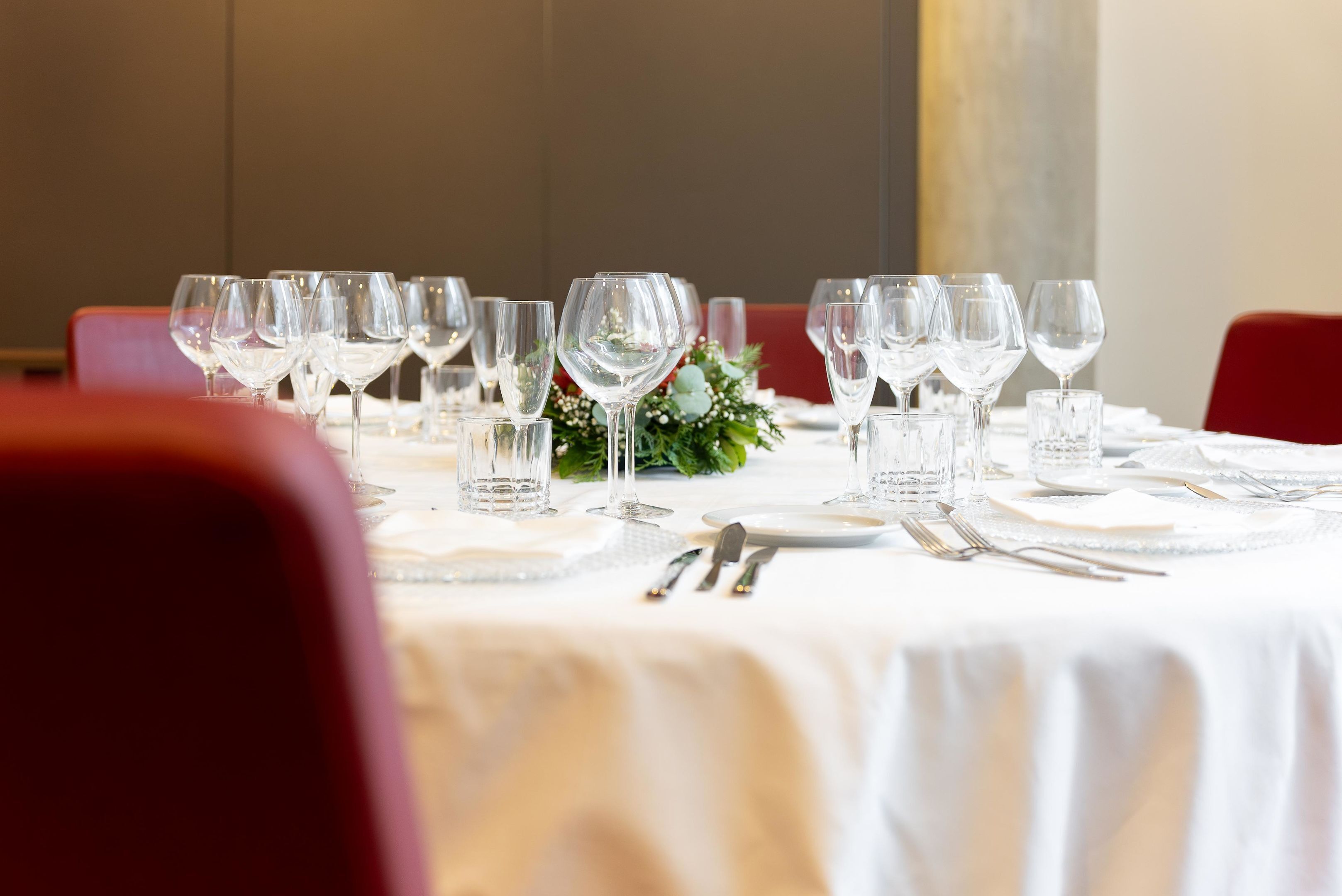 Ein Tisch ist für ein festliches Essen gedeckt, mit mehreren Weingläsern, Wassergläsern und Besteck.