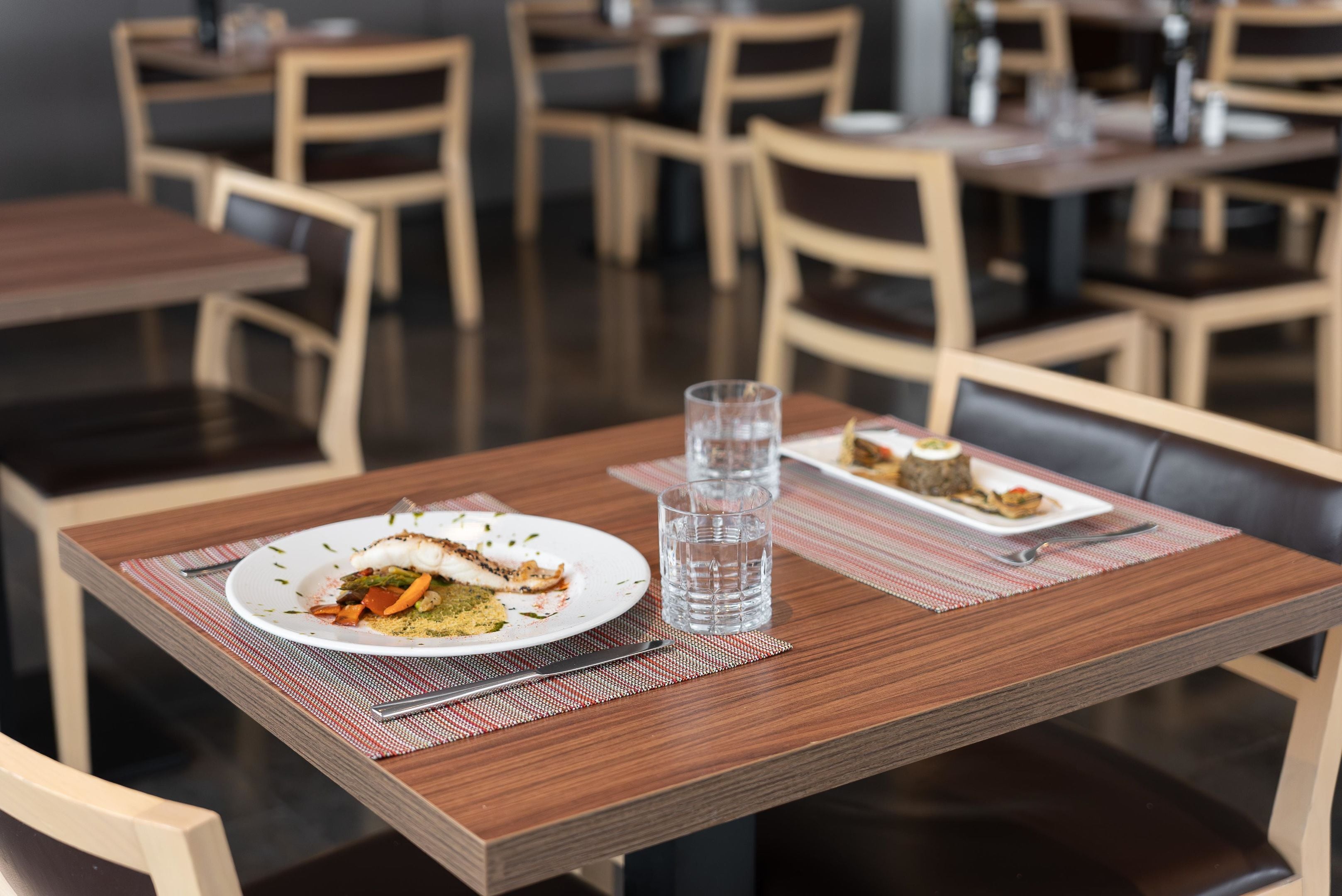 A dining table with a plate of food, a glass of water, and a napkin.