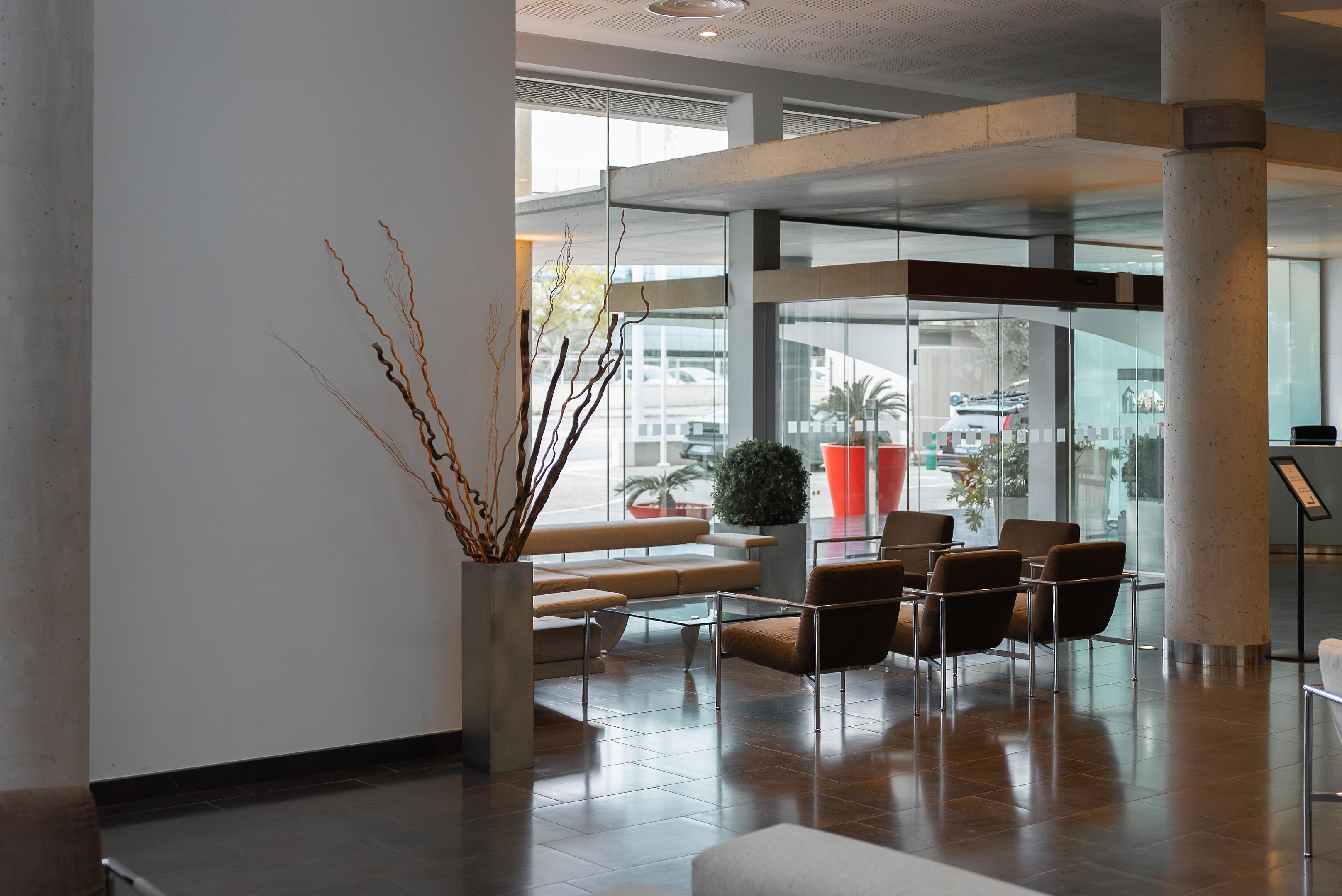 A modern lobby with a seating area, a glass partition, and a view of the outside.