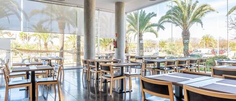 Un amplio comedor interior con ventanas grandes, mesas y sillas de madera.