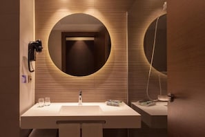 A modern bathroom with a large mirror, a sink, and a towel rack. - Hotel Port Elche (Elche)
