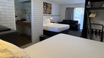 Une chambre d’hôtel comprenant un lit, un bureau, une chaise, un canapé noir et un mur orné d’un élément décoratif.