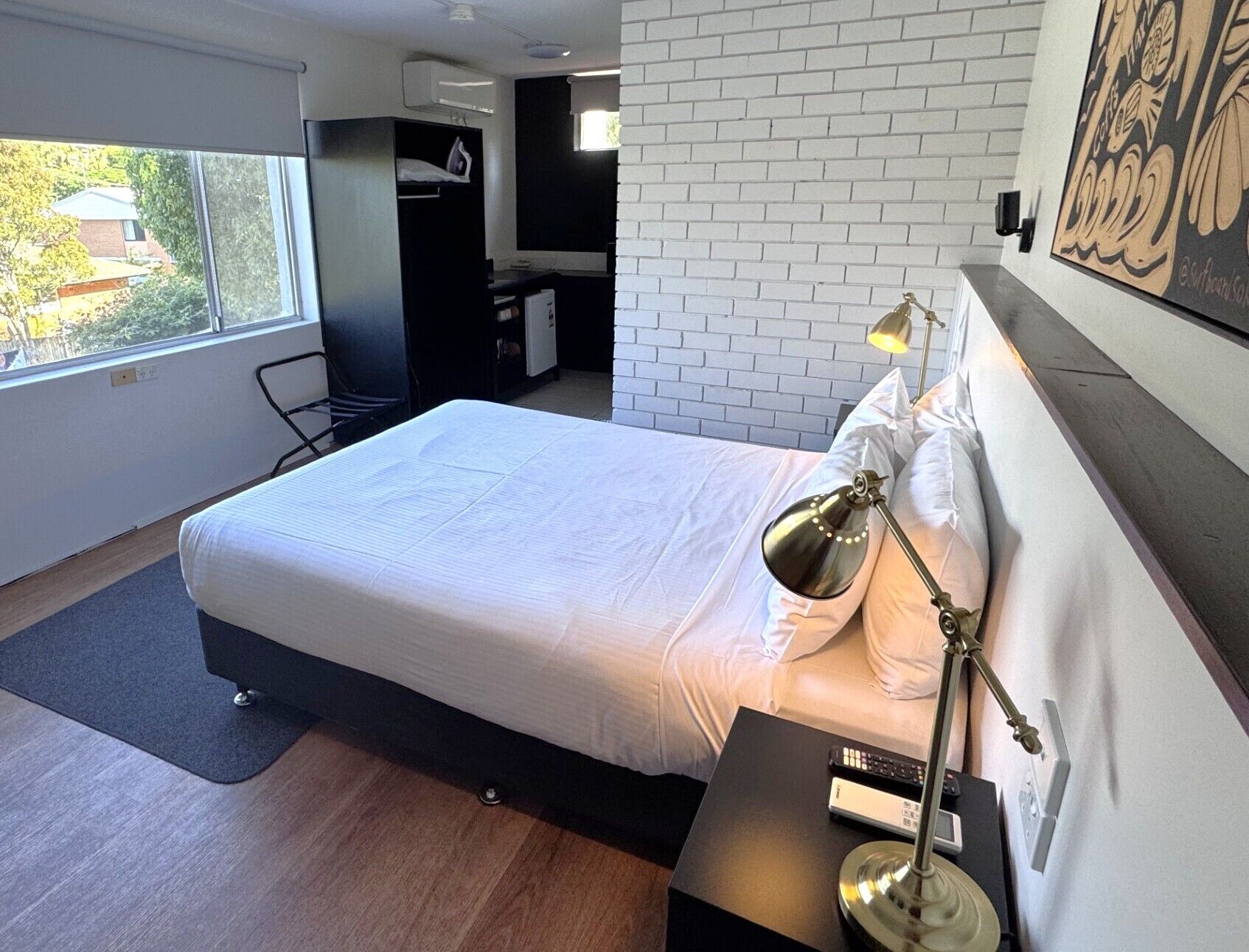 Ein modernes Hotelzimmer mit einem großen Bett, einem Schreibtisch, einem Stuhl und einem Fenster mit Blick auf Gebäude.