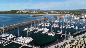 A marina with numerous boats docked, a pier extending into the water, and a backdrop of hills and buildings. - Matador Motor Inn (Coffs Harbour)