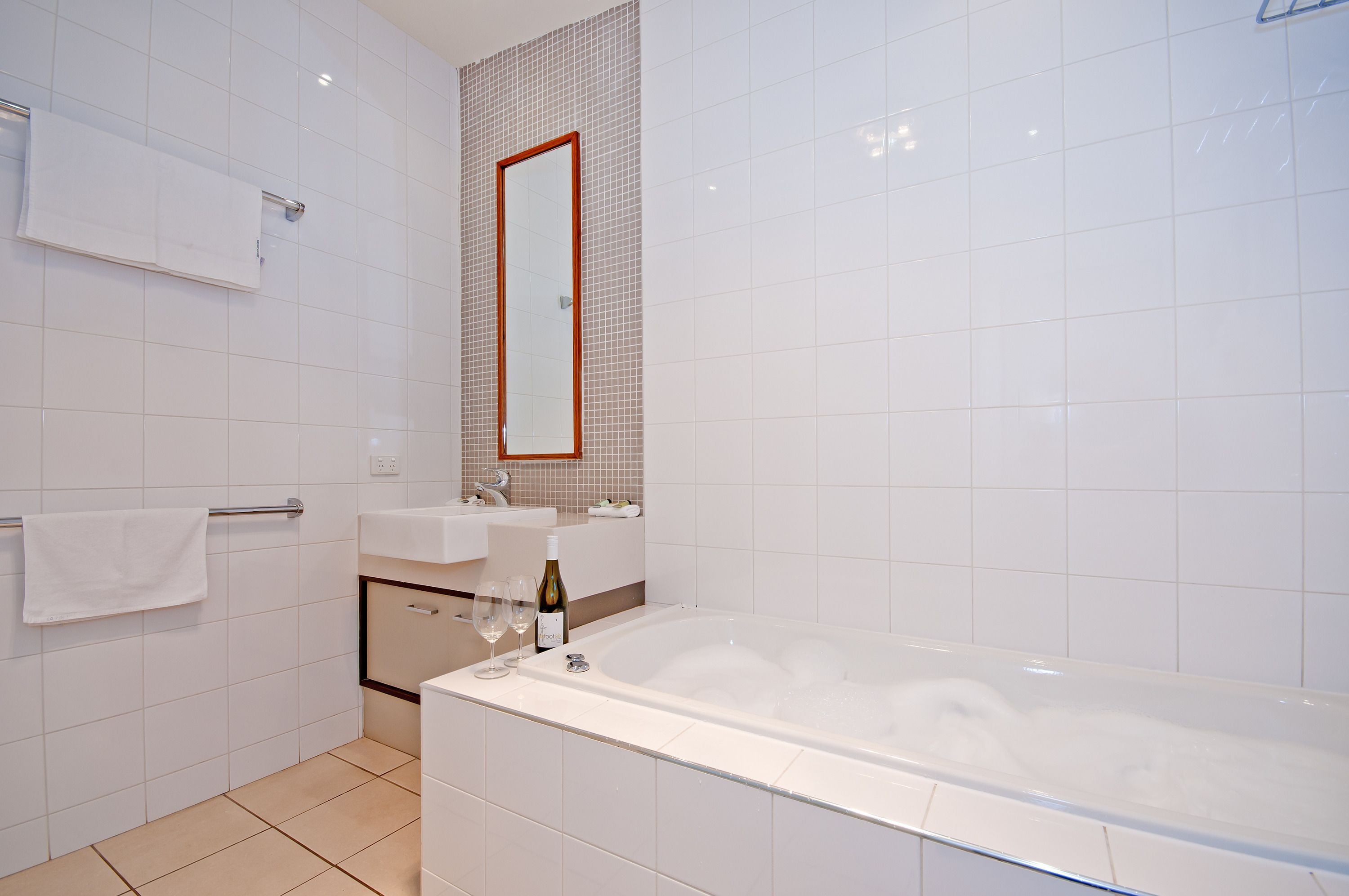 A modern bathroom with a bathtub, two sinks, a mirror, and a towel rack.