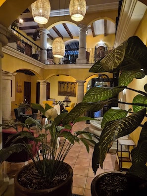 A multi-level atrium with a central staircase, potted plants, and a seating area with tables and chairs.