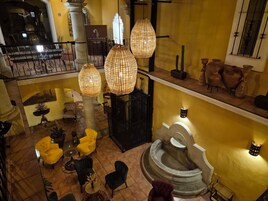 Interior com vários níveis, uma escadaria central, iluminação decorativa e diferentes opções de assentos.