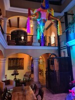 Amplo espaço interno com teto alto, destacando um pilar central, uma mesa de jantar com cadeiras e uma área de estar com sofás.