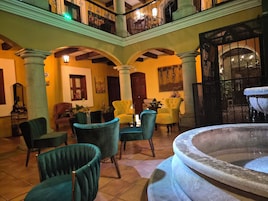 A spacious lobby with a fountain, multiple seating areas, and a balcony with ornate railings.
