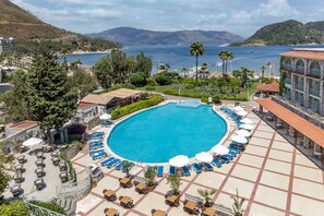 A resort with a large pool surrounded by lounge chairs and umbrellas, overlooking a beach and the sea. - Marti La Perla Hotel - All Inclusive - Adult Only (Marmaris)