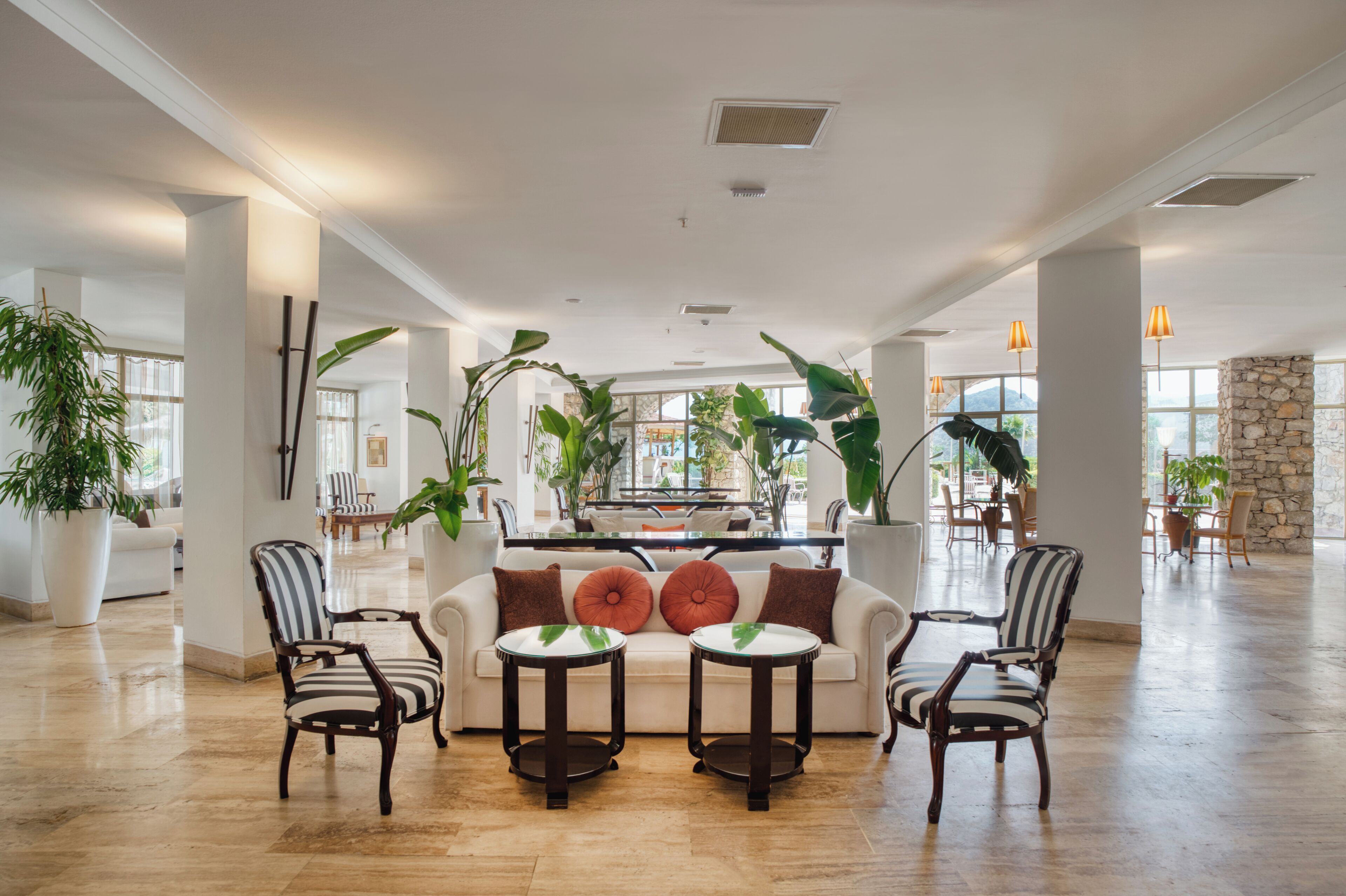 A spacious lobby with a central seating area, large windows, and potted plants.