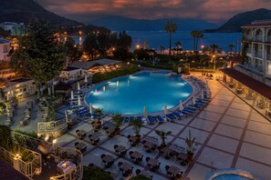 A resort with a large swimming pool surrounded by lounge chairs and tables, set against a backdrop of mountains and a body of water. - Marti La Perla Hotel - All Inclusive - Adult Only (Marmaris)