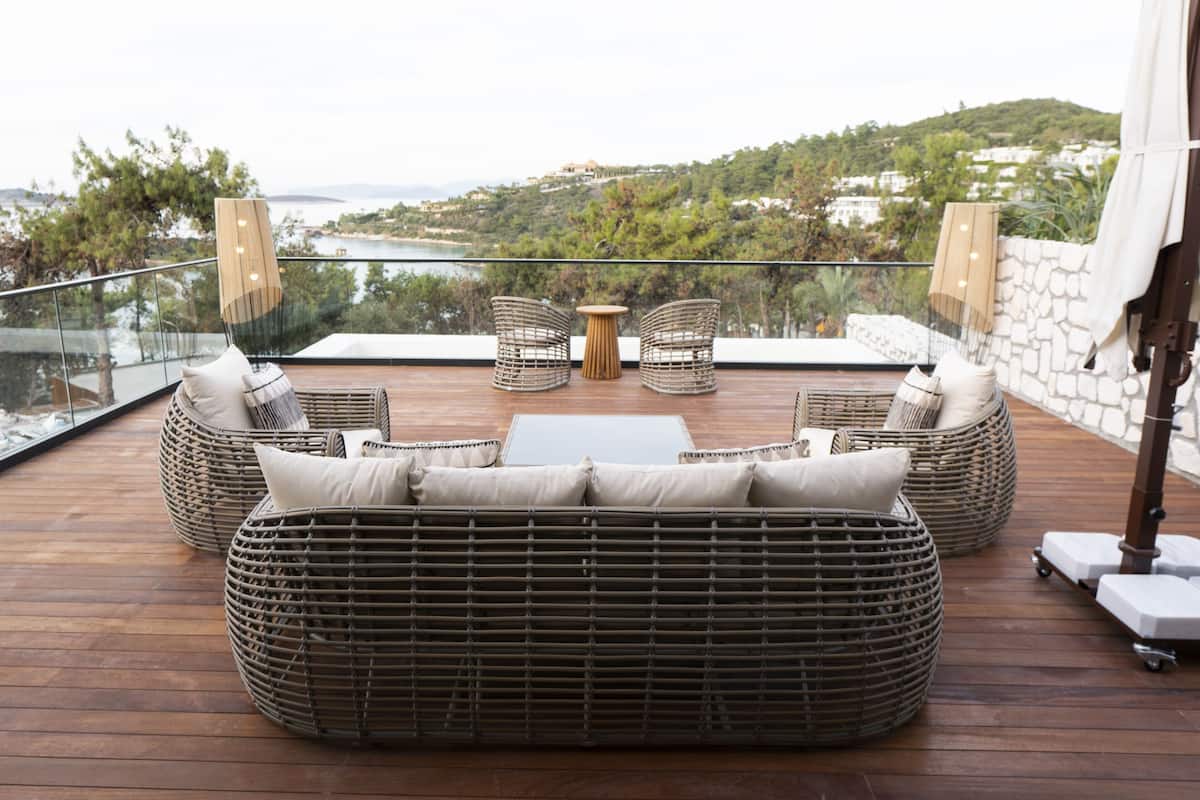 A balcony with wicker furniture, a small table, and a view of the landscape.