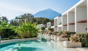 A pool area with a mountain in the background, surrounded by white buildings with balconies.