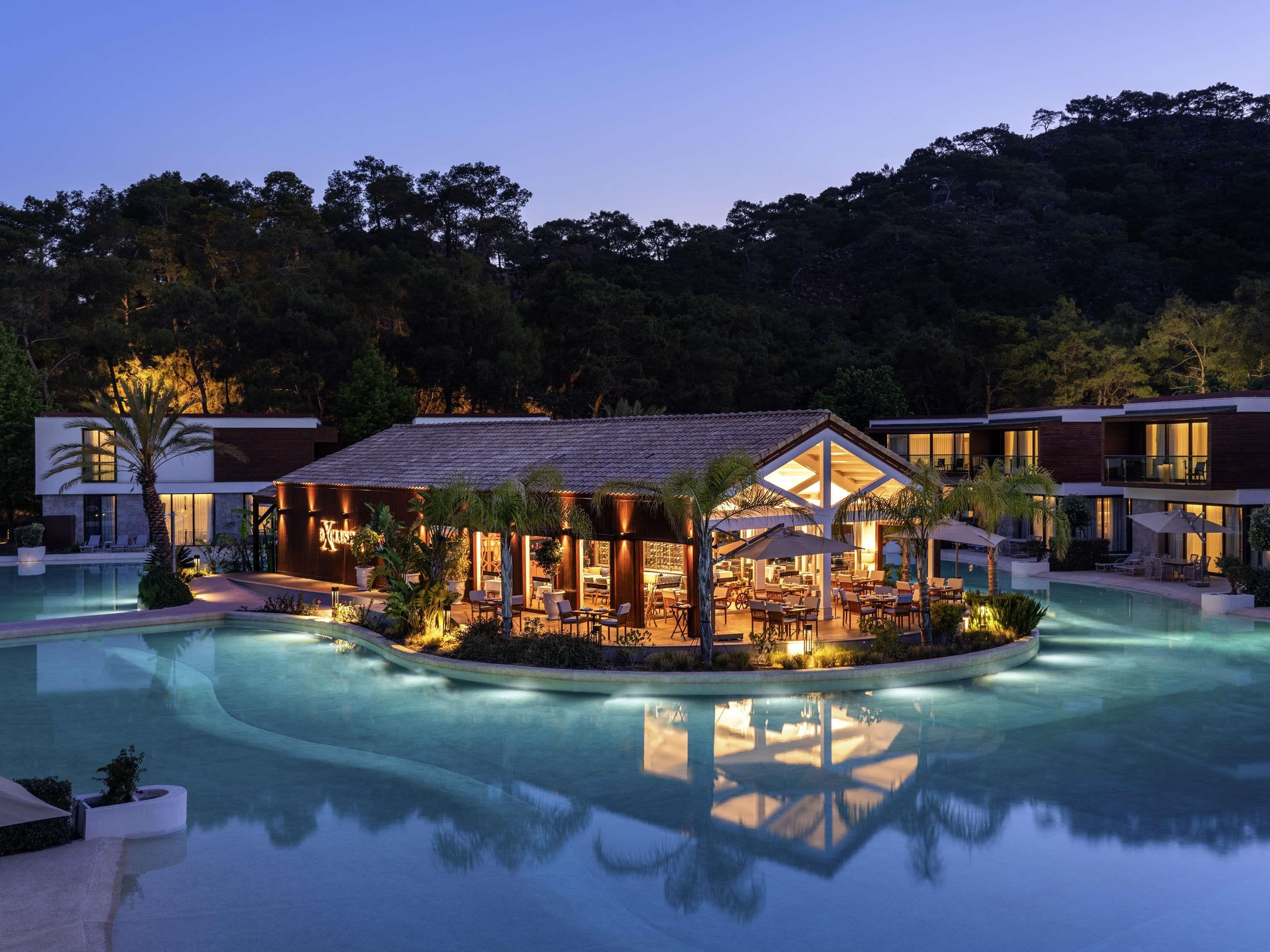 A modern resort with a pool, outdoor seating, and a building with large windows.