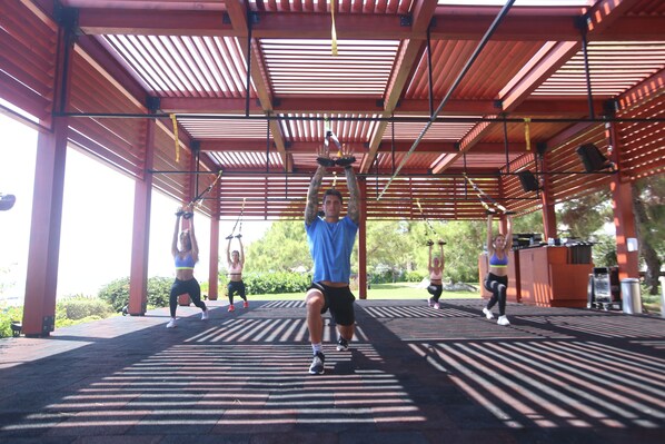 An outdoor gym with a covered roof and exercise equipment.
