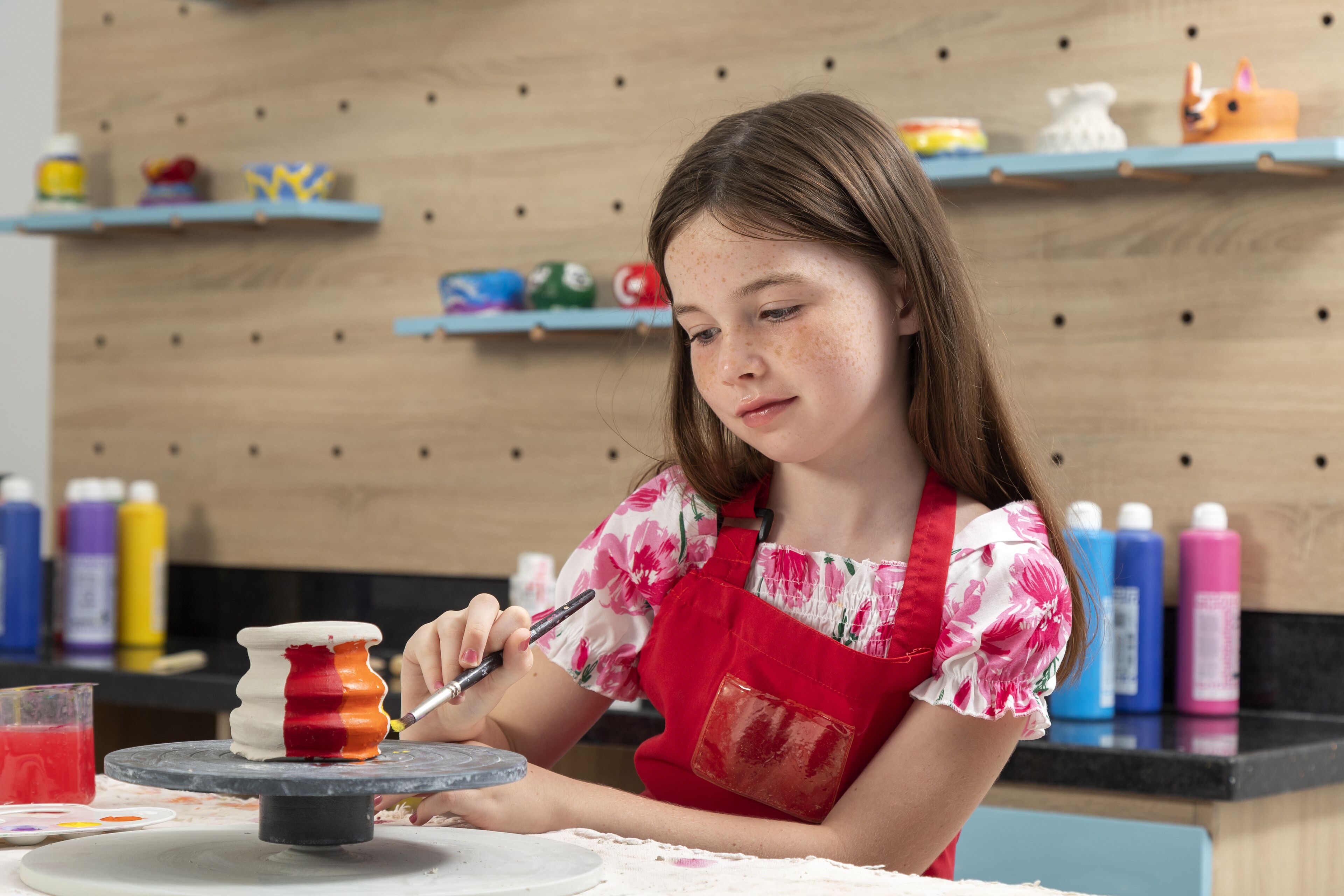A person painting a ceramic object on a rotating wheel.