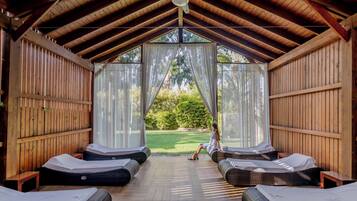 Relax in a serene spa room with a high ceiling, lounge chairs, and a view of the manicured lawn.