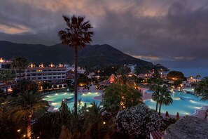 A resort with multiple swimming pools, palm trees, and a mountainous backdrop. - Marti Resort Hotel (Marmaris)