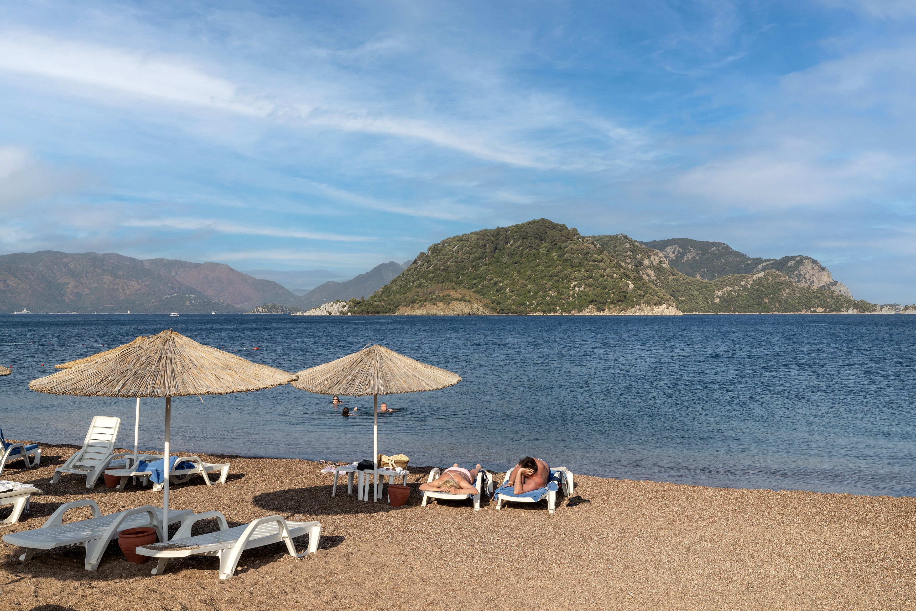 A beach with sun loungers, umbrellas, and a calm sea.