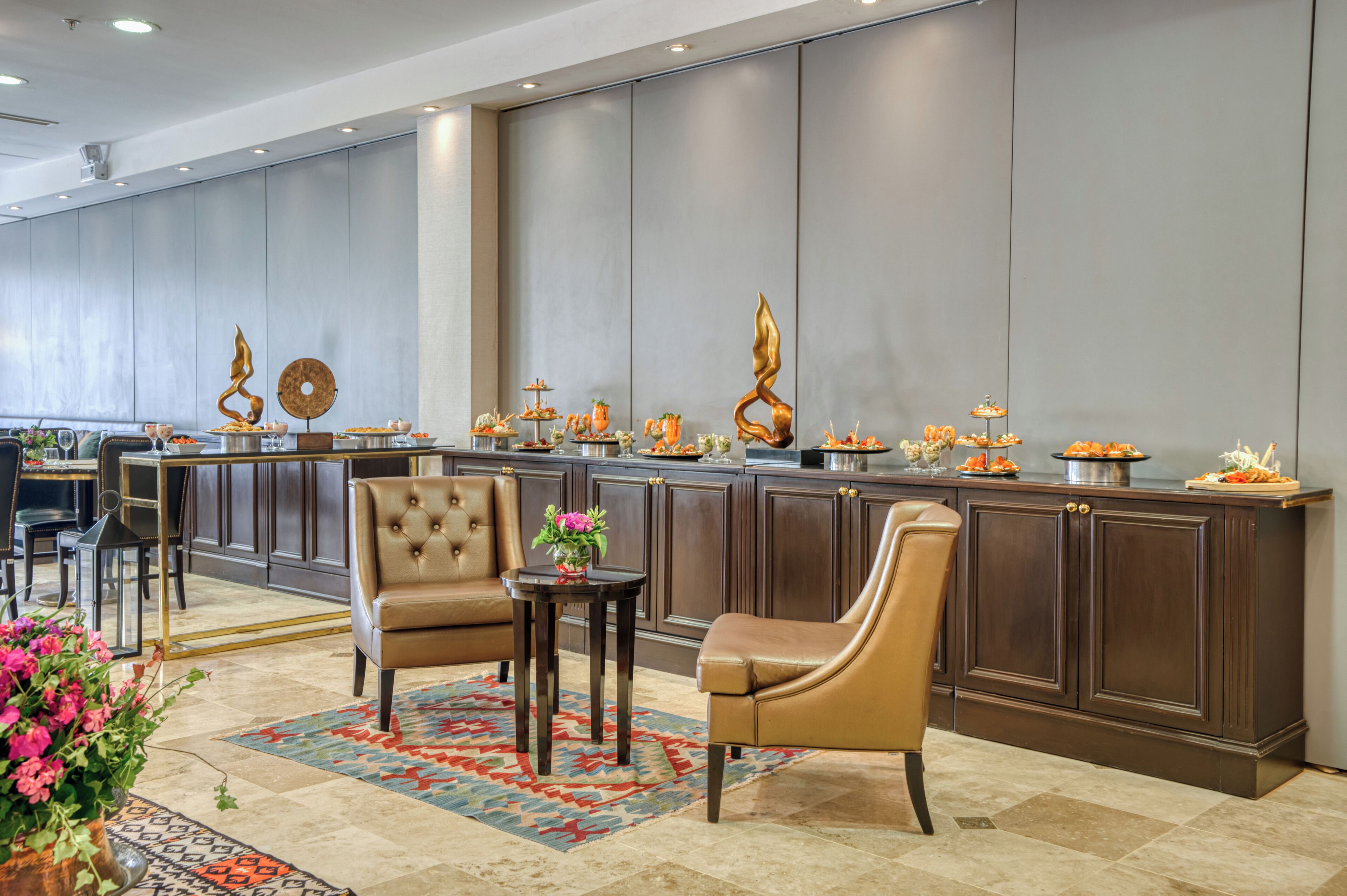 A modern hotel lobby with a long reception desk, leather seating, and a decorative rug.