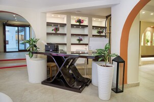 A reception desk with a glass top, white cylindrical planters, and a modern interior design.