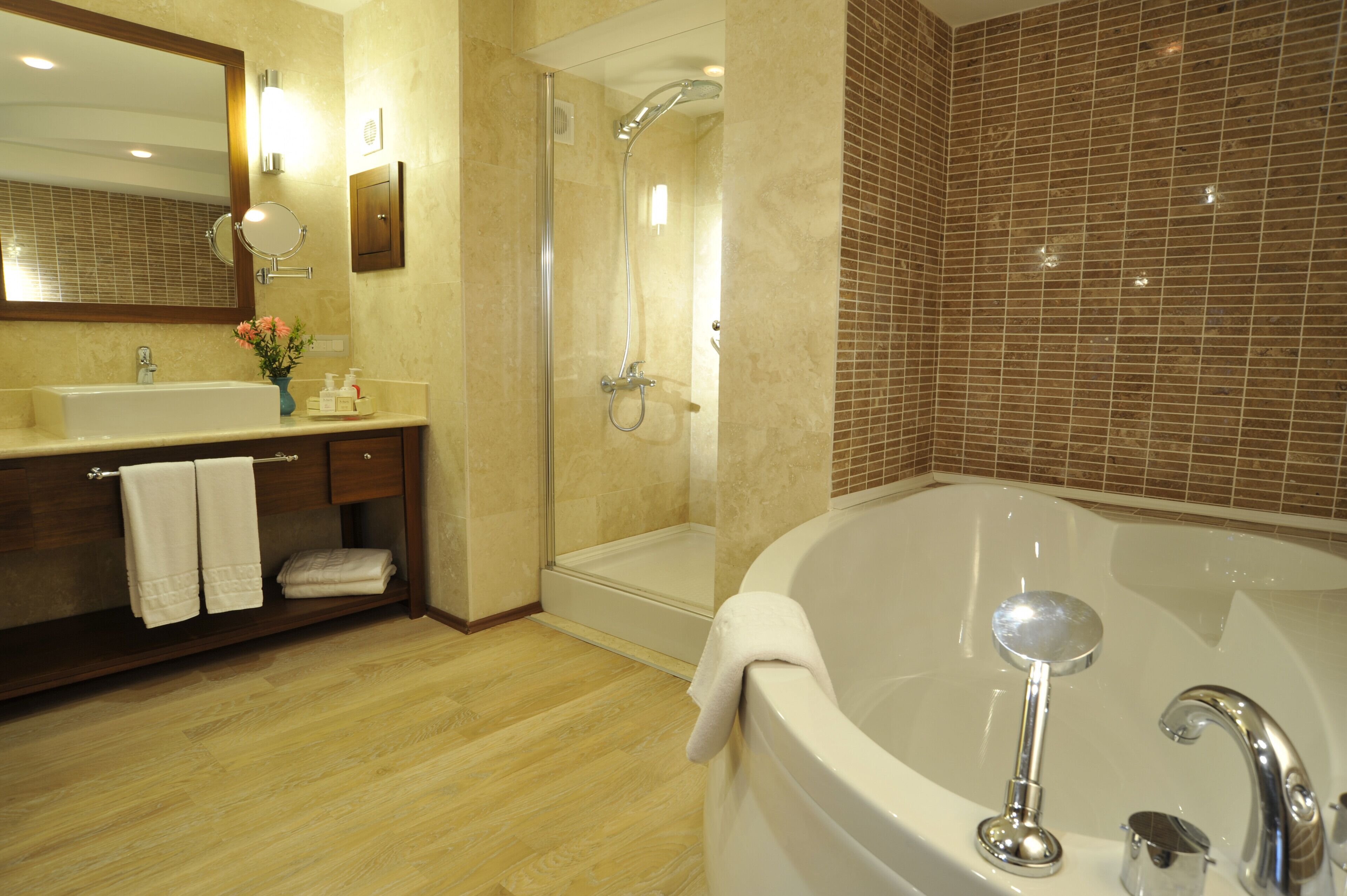A modern bathroom with a large bathtub, a separate shower area, and a vanity with a mirror and towel rack.
