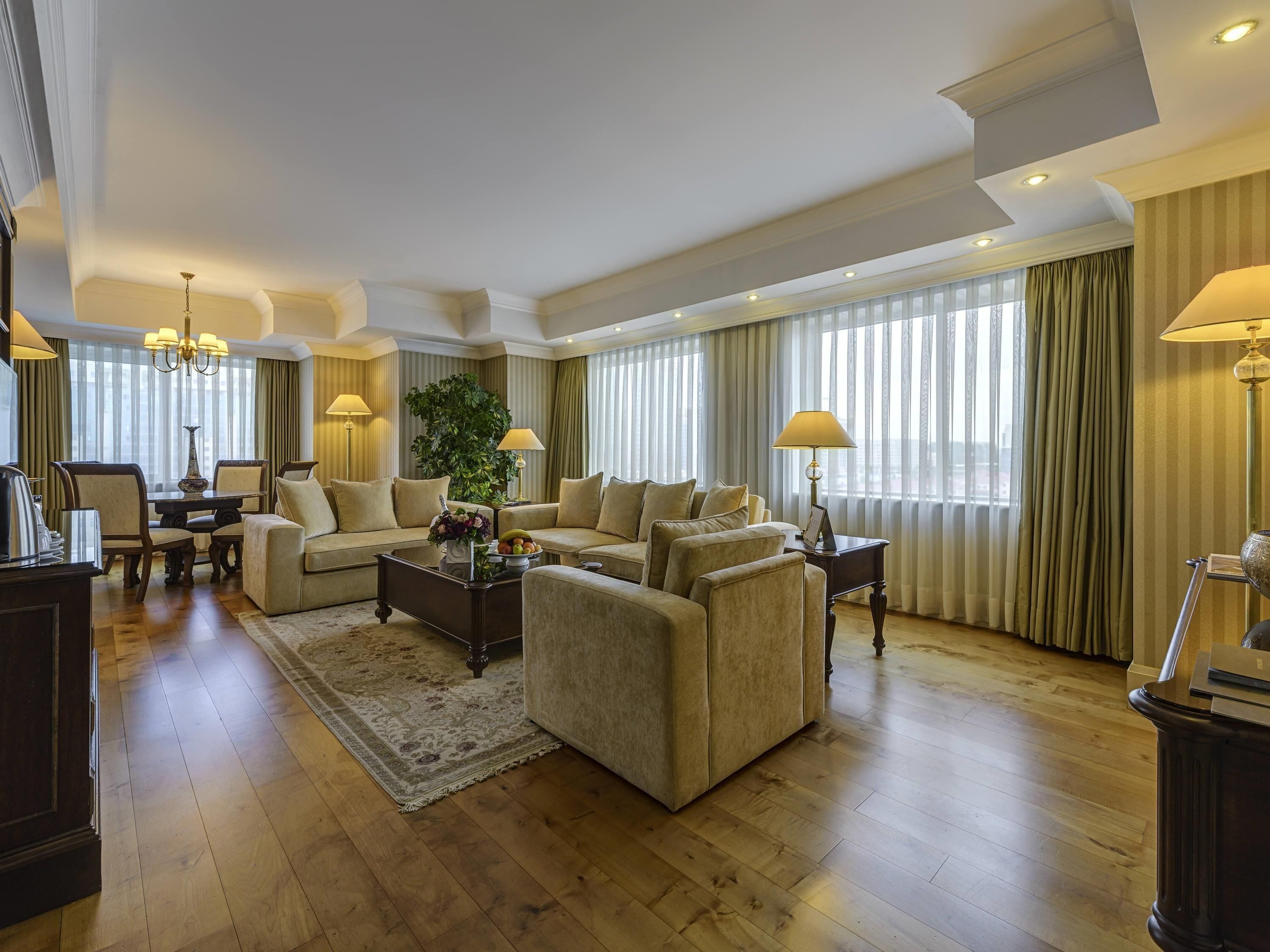 A spacious living room with a large sofa set, a coffee table, and a dining area with chairs and a table.
