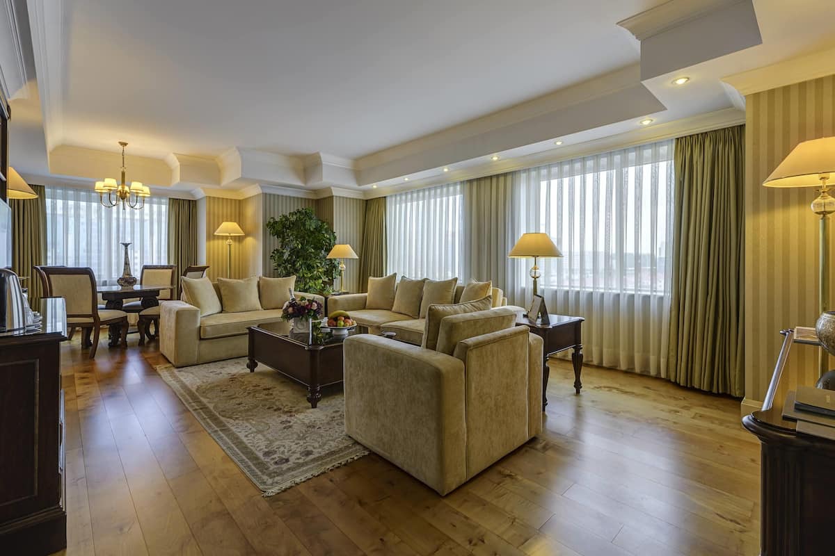 A spacious living room with a large sofa set, a coffee table, and a dining area with chairs and a table.