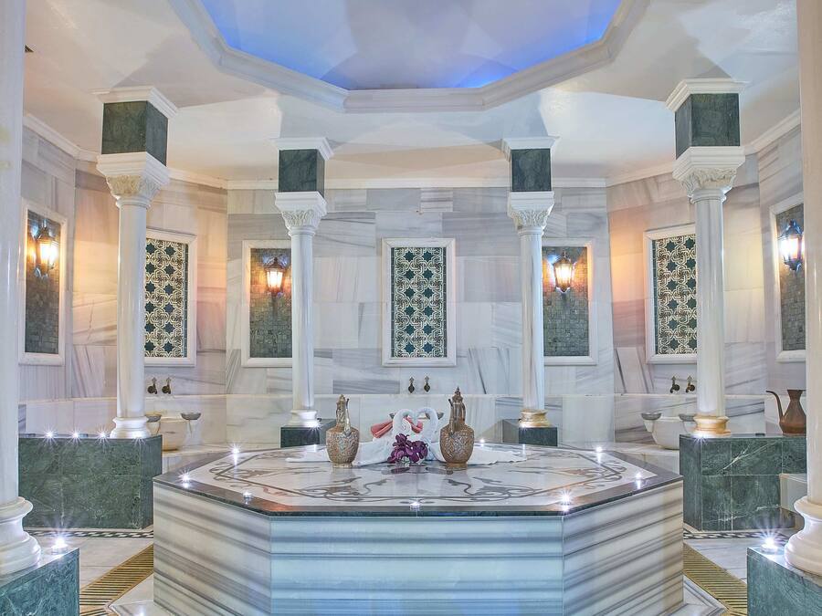 A luxurious lobby with marble floors, a central island with decorative items, and patterned wall panels.