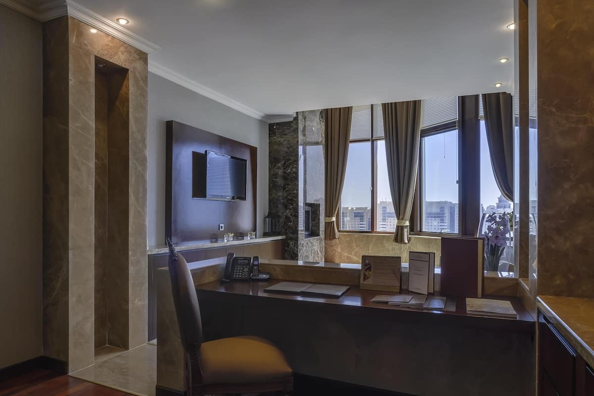 A hotel reception desk with a flat-screen TV, a telephone, and a window with curtains.