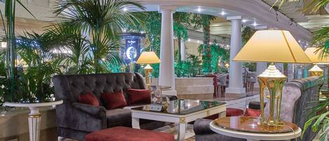 A luxurious lobby with a grand sofa, elegant lamps, and lush greenery.