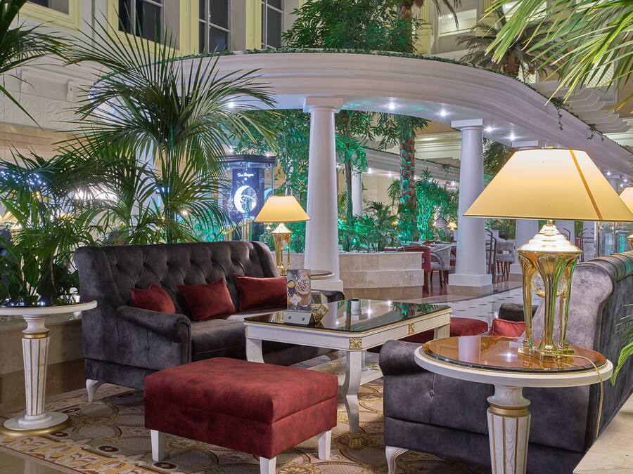 A luxurious lobby with a grand sofa, elegant lamps, and lush greenery.