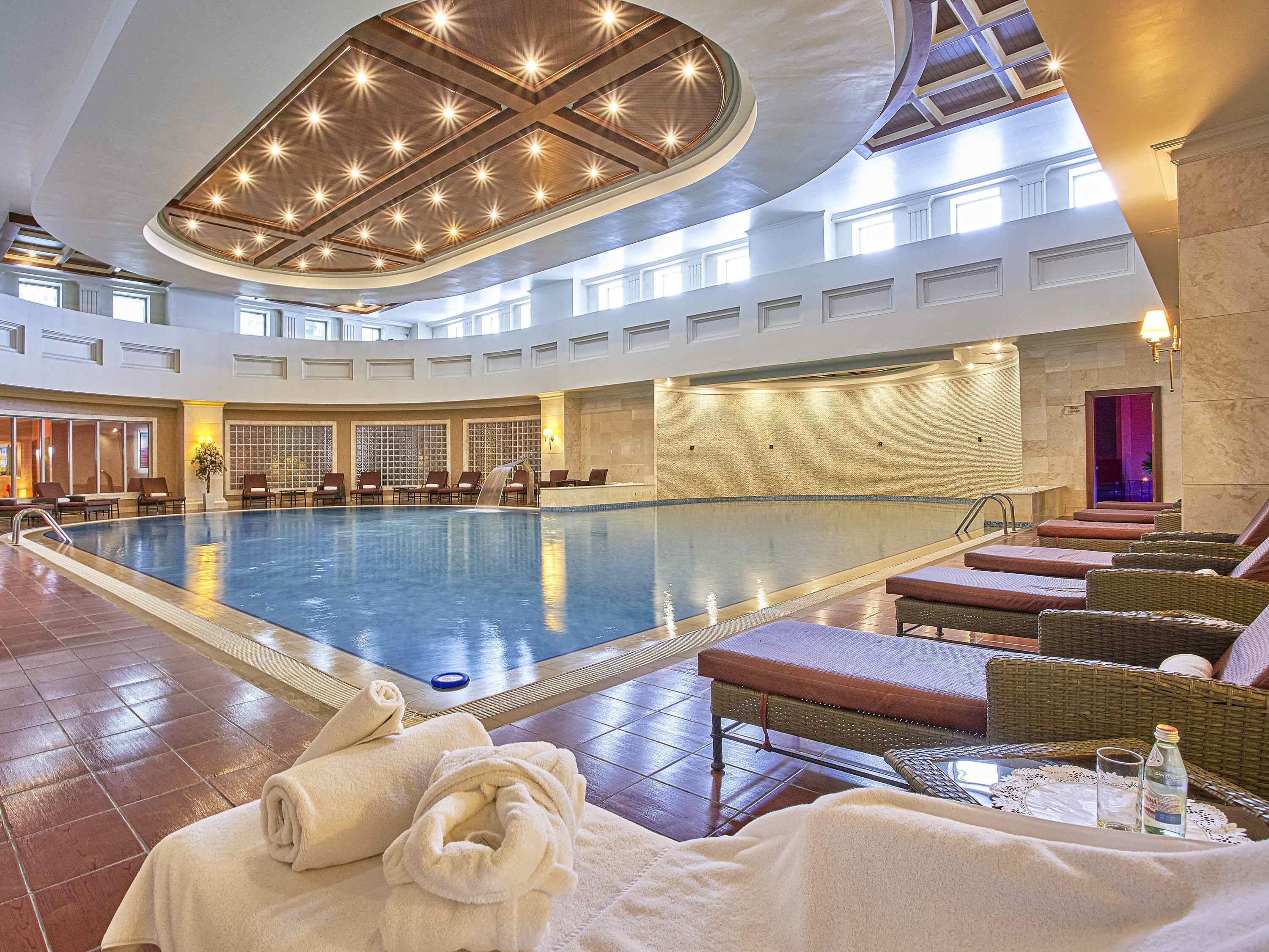 Una gran piscina interior con sillones de descanso y una cascada.