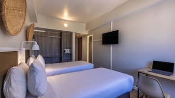 Une chambre d’hôtel avec deux lits, un bureau avec un ordinateur portable, une télévision et un four à micro-ondes.