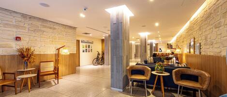Eine moderne Lobby mit Steinwand, Holzmöbeln und einem Empfangstresen.