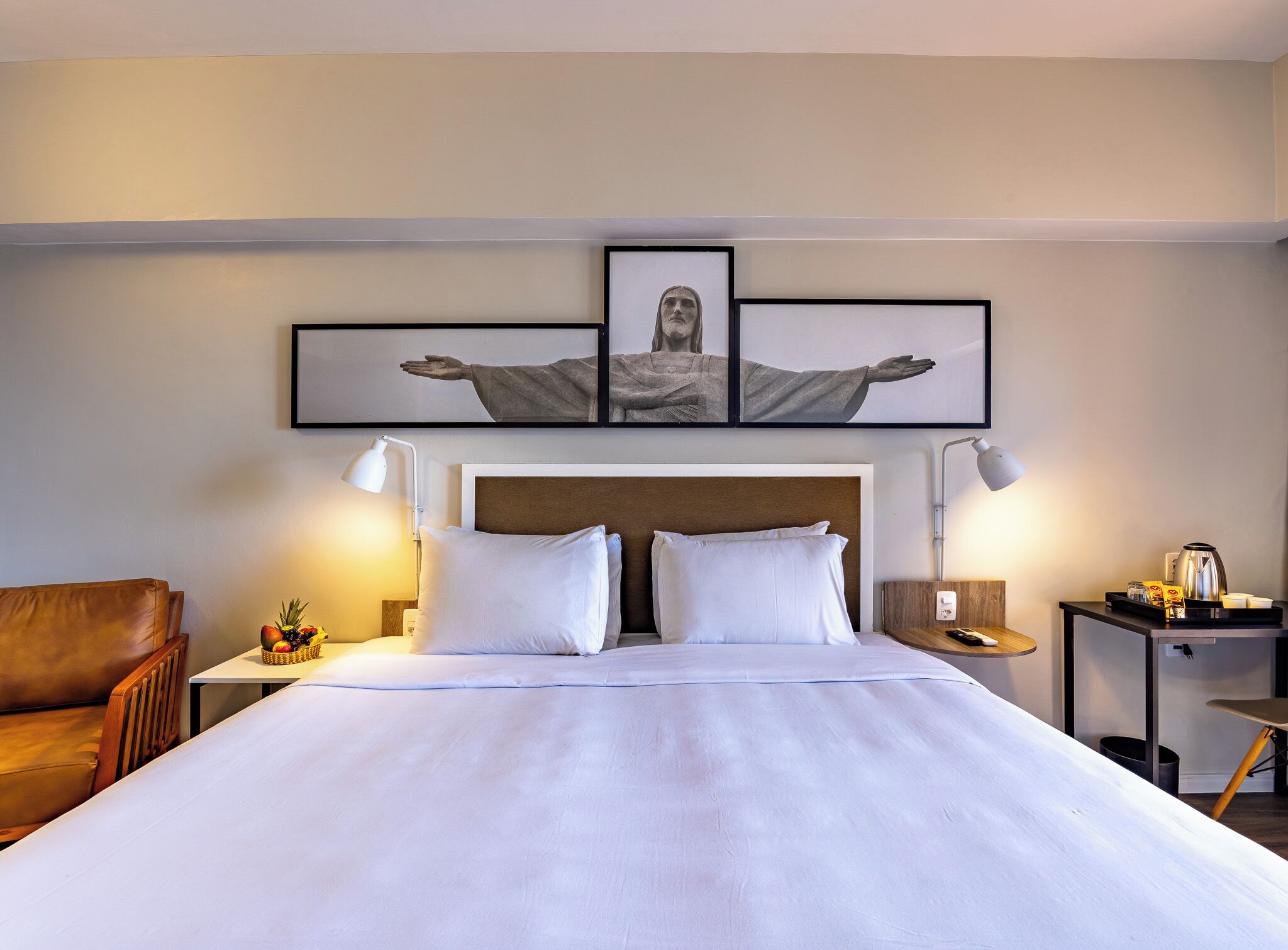 Una habitación de hotel con una cama grande, dos mesitas de noche, una silla y una obra de arte colgada en la pared.