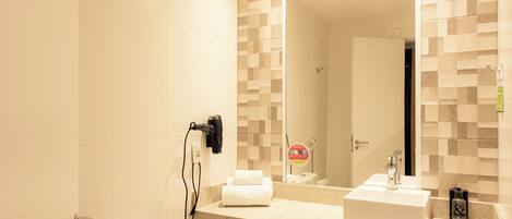 A bathroom with a white toilet, a sink with a mirror above it, and a towel rack with towels.