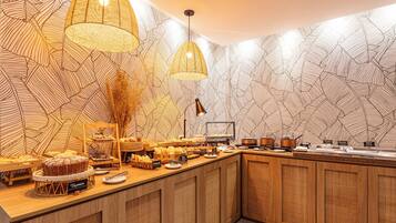 A buffet area with a variety of food items and a decorative wall with leaf patterns.