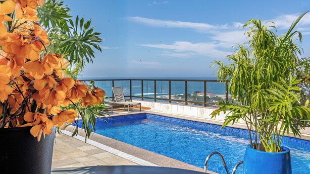 A rooftop pool with a view of the ocean, surrounded by potted plants and a lounge chair. - B&B Hotels Rio Copacabana Posto 5 (Rio de Janeiro)