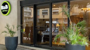 A hotel entrance with a large glass door, potted plants, and a sign reading "B&B HOTELS". - B&B Hotels Rio Copacabana Posto 5 (Rio de Janeiro)