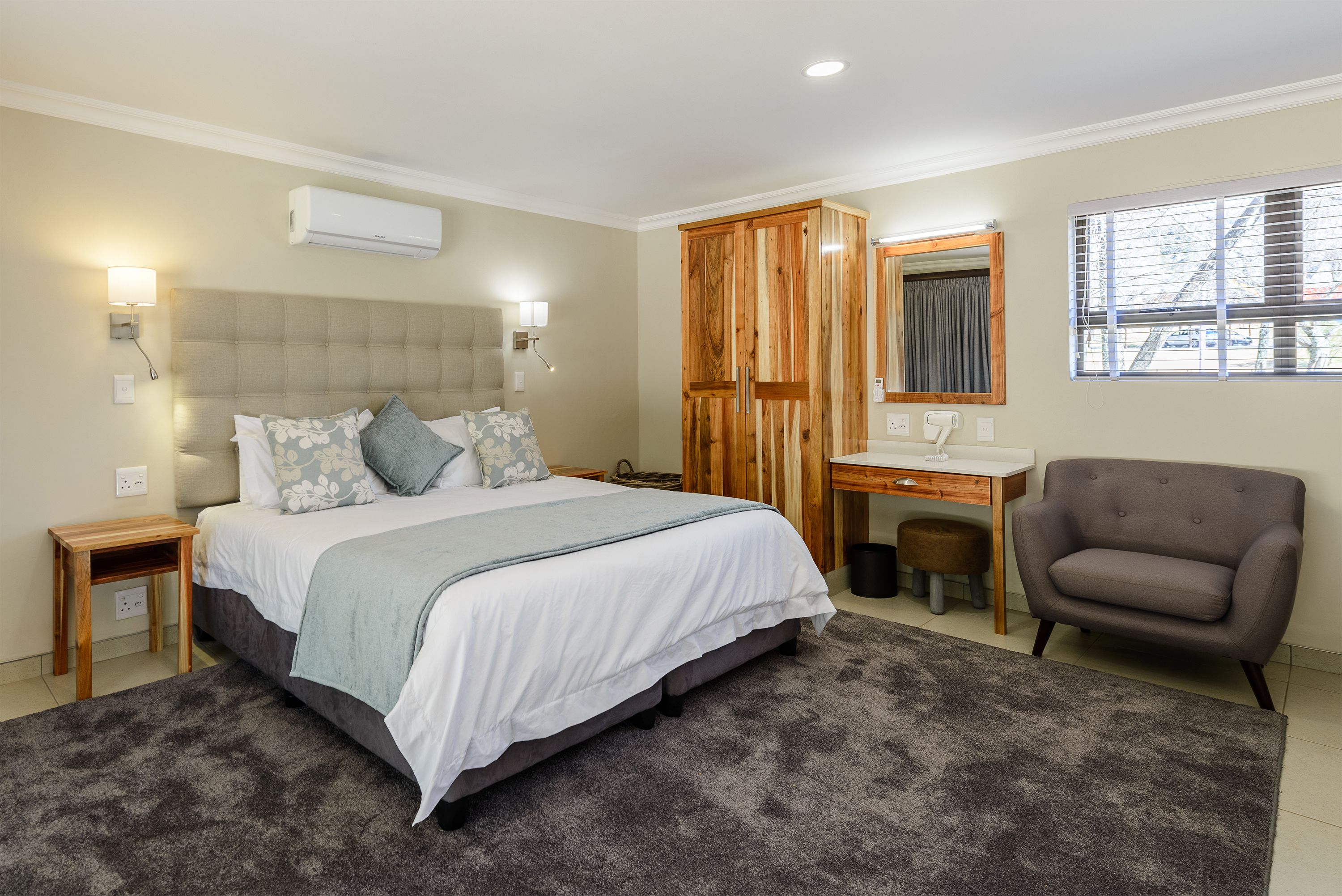 A bedroom with a bed, bedside tables, a desk, a chair, and a wardrobe.