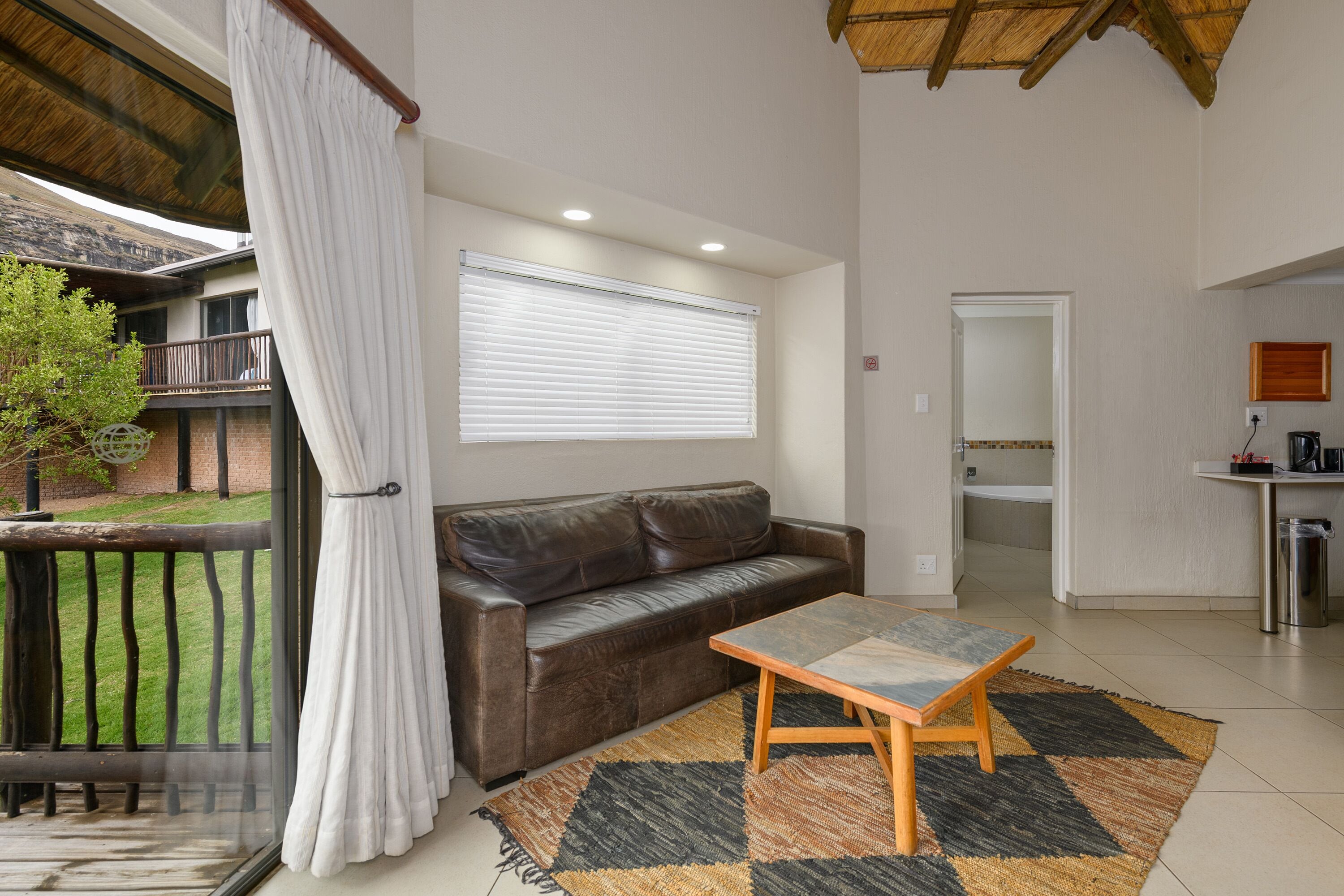 A living room with a brown leather sofa, a wooden coffee table, and a patterned rug.
