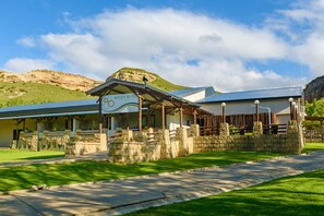 A hotel with a sign reading "BODY BLISS" and a mountainous backdrop. - Kiara Lodge (Clarens)