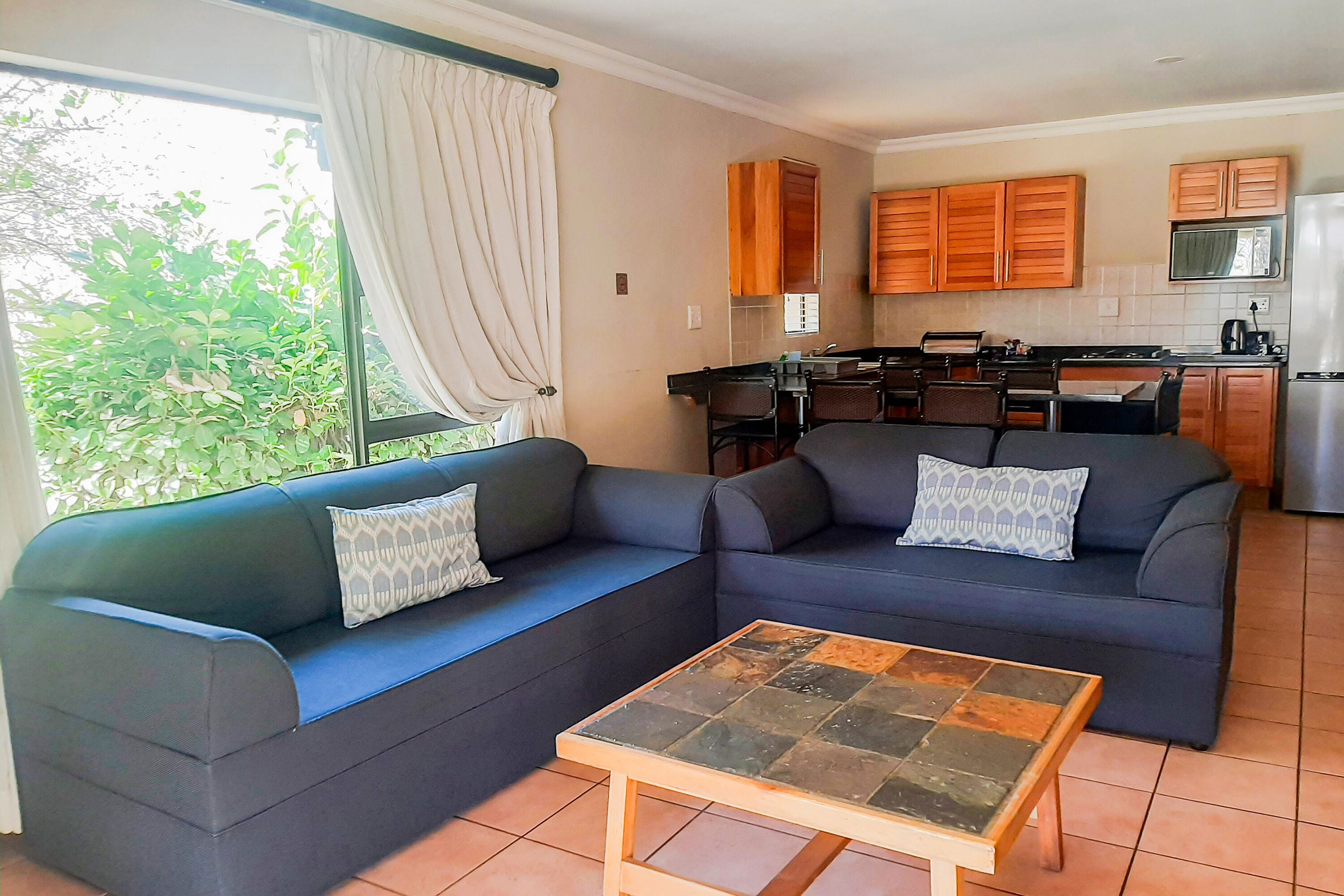 A living room with two sofas, a coffee table, and a kitchen in the background.