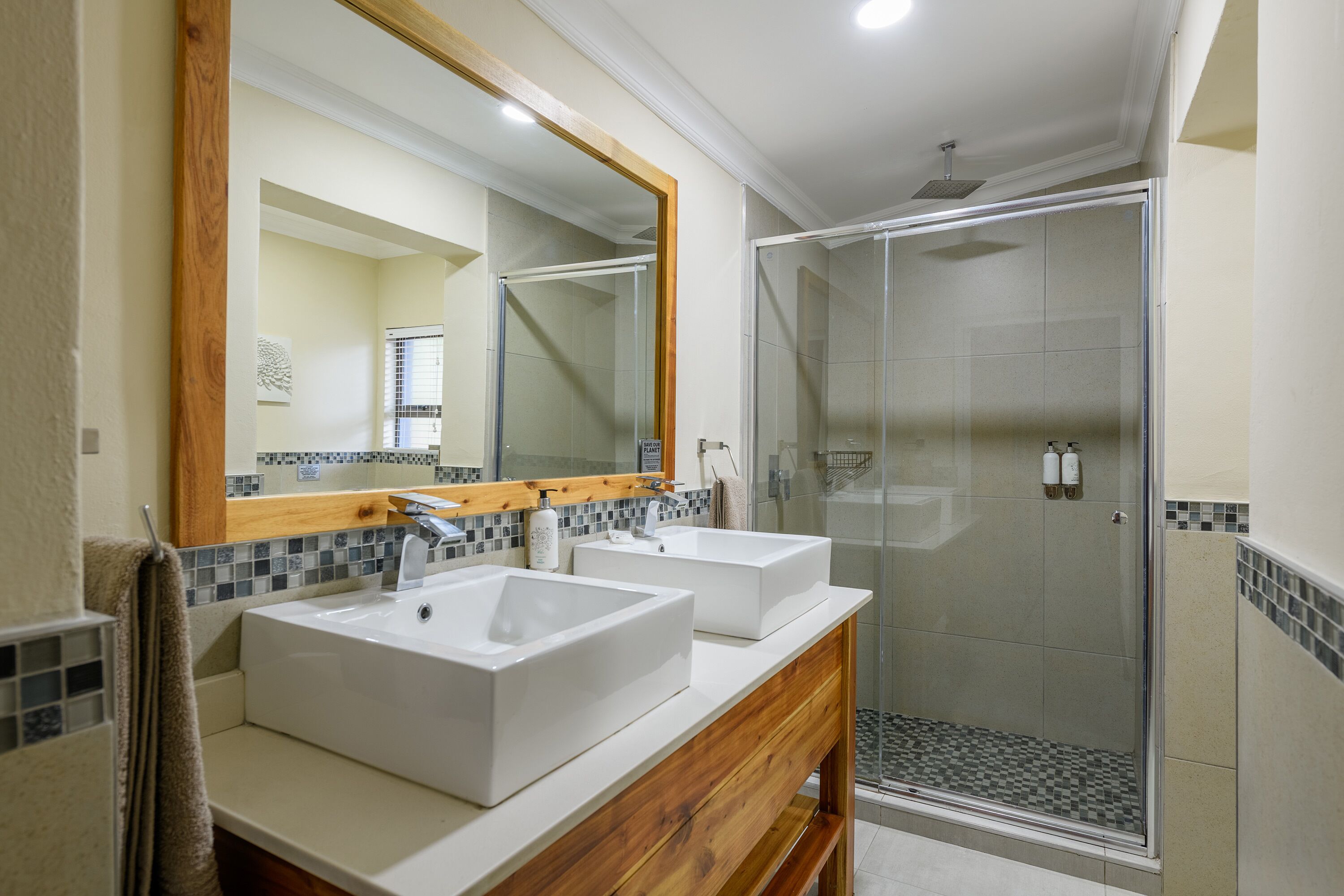 Un baño con dos lavamanos, una ducha y un espejo grande.