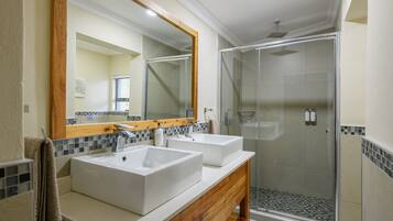 Un baño con dos lavamanos, una ducha y un espejo grande.