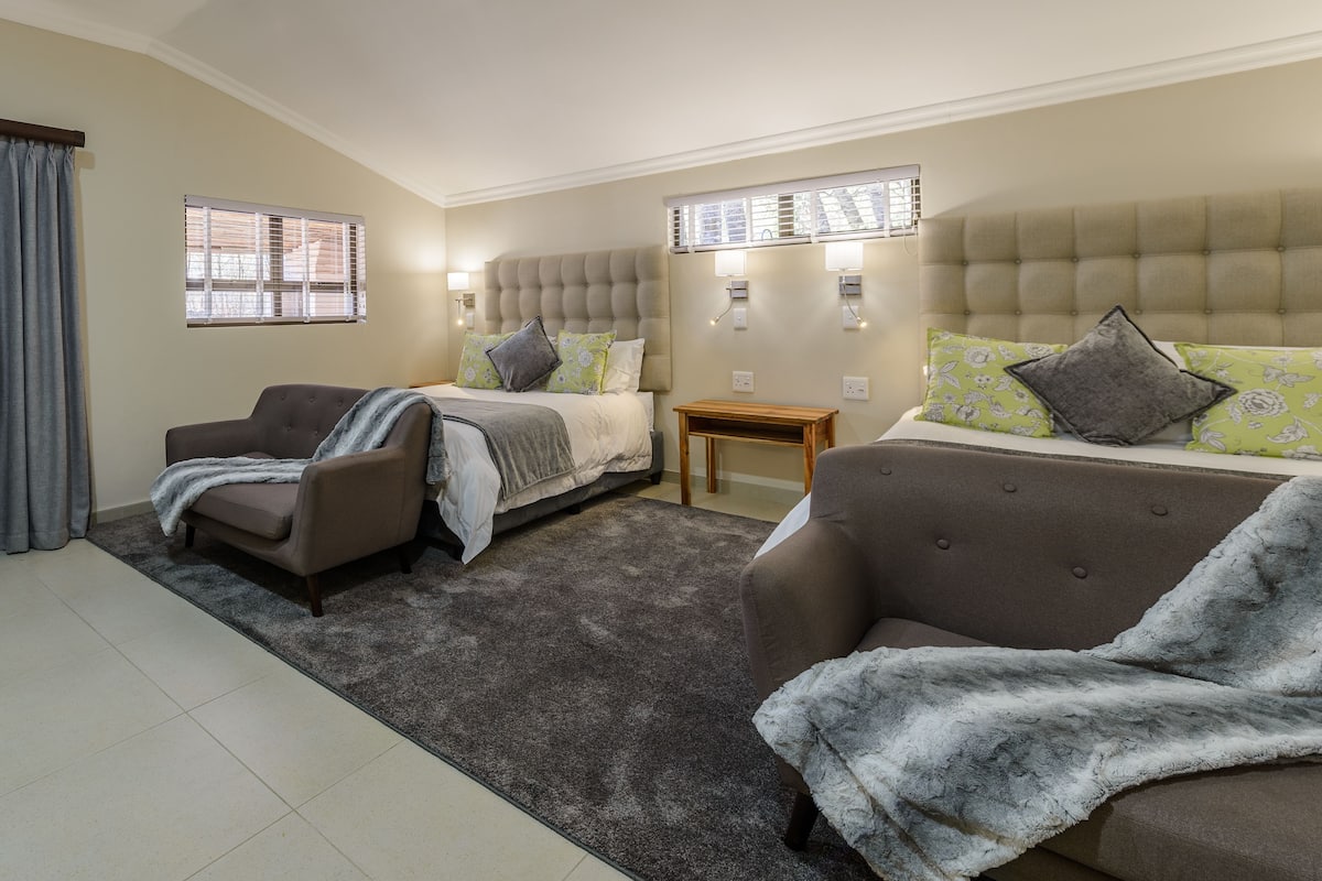 A bedroom with two beds, a sofa, a chair, and a small table.