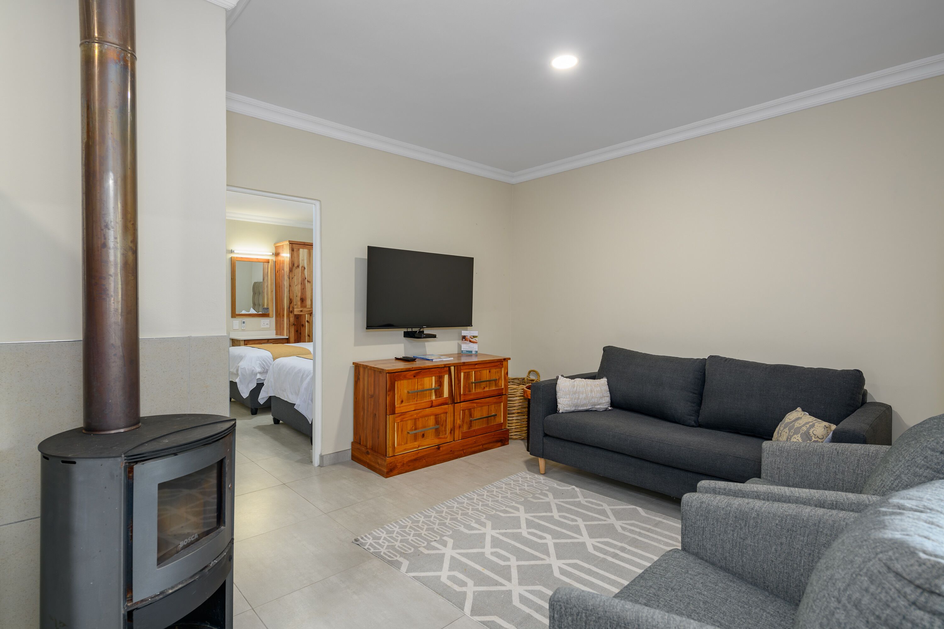 A living room with a fireplace, sofa, TV, and wooden cabinet.